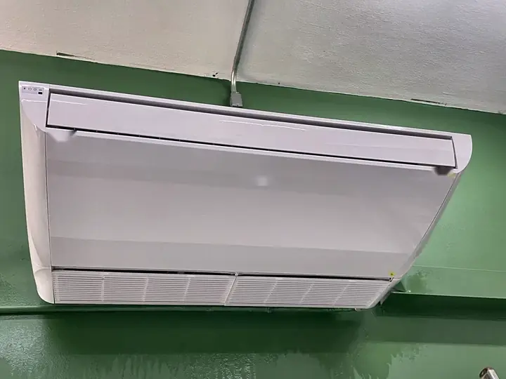 Ar-condicionado piso-teto recém-instalado em parede verde, com eletroduto de alimentação