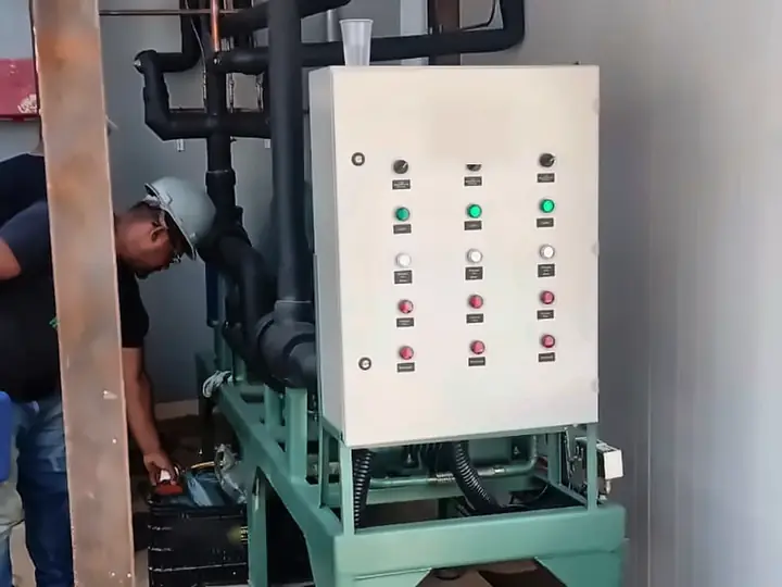 Técnico conferindo um rack de compressores com quadro de comando instalado sob cobertura