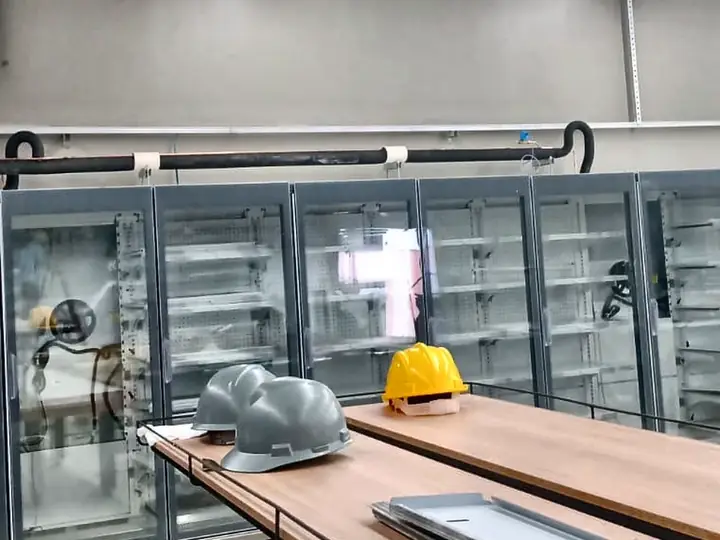 Expositores refrigerados com portas de vidro instalados em loja, com tubulação isolada acima