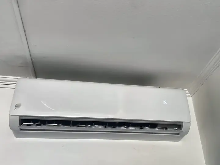 Ar-condicionado split instalado em canto de sala, junto à moldura de gesso