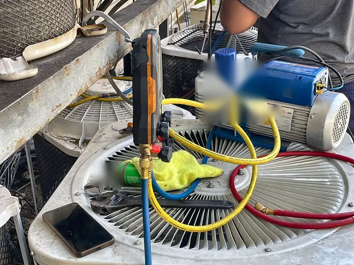 Técnico fazendo vácuo com manifold digital e bomba de vácuo na condensadora