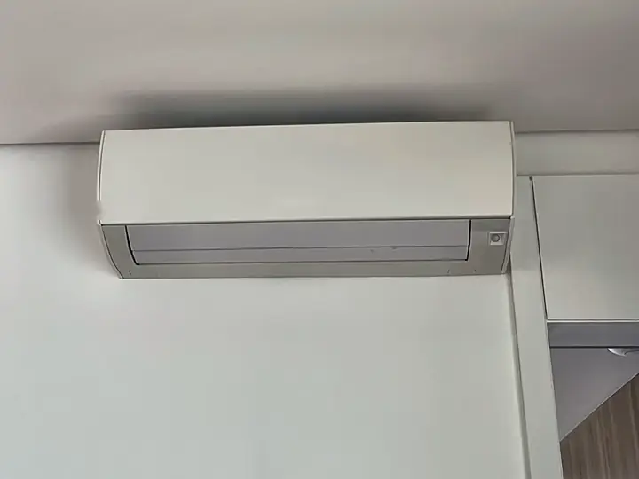 Ar-condicionado split instalado no canto da parede, ao lado de um armário