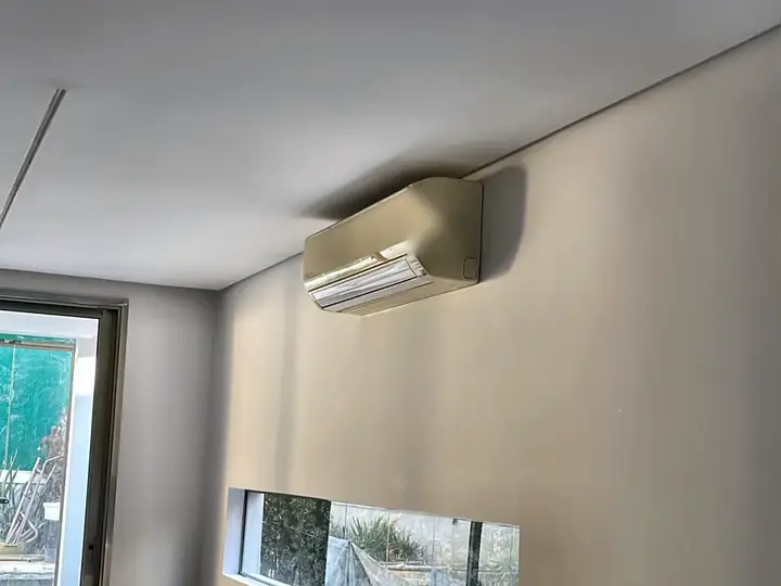 Ar-condicionado split instalado em sala com janela horizontal e sofá