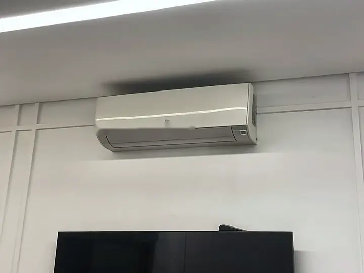 Ar-condicionado split instalado acima da TV em parede com boiserie