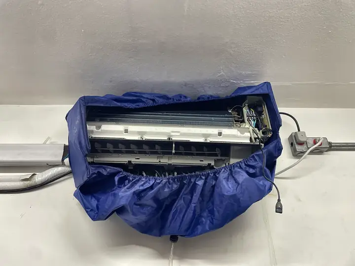 Evaporadora de ar-condicionado split aberta dentro de bolsa coletora azul para higienização