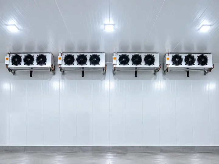 Quatro evaporadores instalados lado a lado na parede de uma câmara fria de grande porte